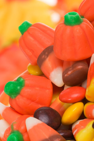Closeup of pumkin filled with delicious  candy over fall leaves background