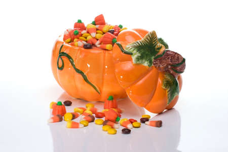Orange pumpkin filled with delicious  corn candy over whiteの写真素材