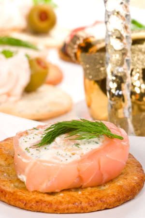 Closeup of cracker with smoked salmon roll with goat cheese and dill on holiday tableの写真素材