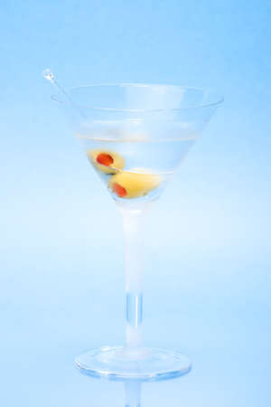 Closeup of martini in glass with two olives over aqua backgroundの写真素材