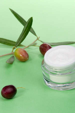 Closeup of jar of moisturizing face cream and olive twig on green toned background の写真素材