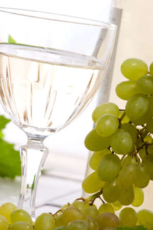 Glass of white wine, bottle and fresh cut green grape bunch.の写真素材