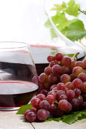 Glass of red wine, decanter and fresh cut red wine grape bunch.の写真素材