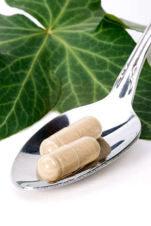 Closeup of herbal supplement pills and fresh ivy leaves best suited for alternative medicine ads. Shallow DOF.の写真素材