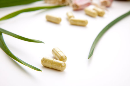 Closeup of garlic extract pills and fresh garlic leaves and cloves best suited for health, anti-cholesterol and alternative medicine adsの写真素材