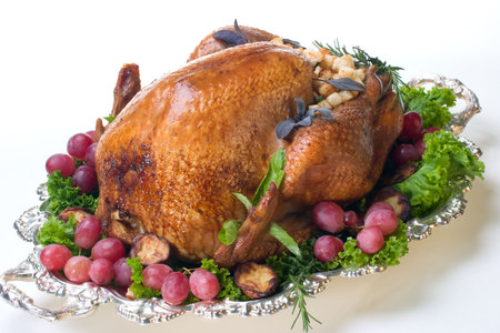 Garnished roasted turkey on platter over white background の写真素材