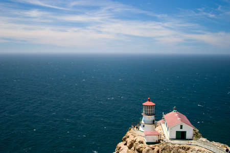 Bluesky seascape with lighthouse on remote capeの写真素材