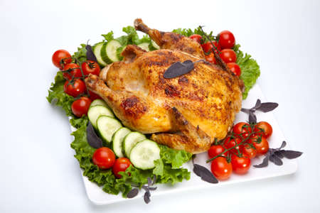 Whole roasted chicken garnished with fresh cucumbers, wine tomatoes, green salad and sage の写真素材
