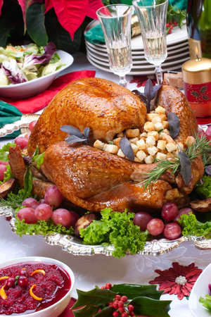 Garnished roasted turkey on Christmas decorated table with candles and flutes of champagneの写真素材