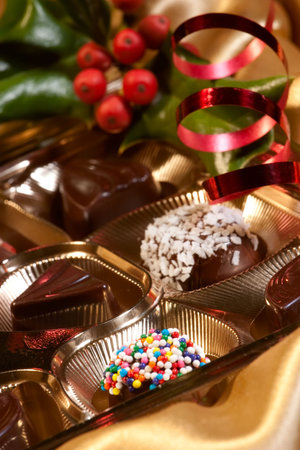 Assorted chocolate candy in a box with Christmas decoration. Shallow DOF.