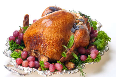 Garnished roasted turkey on platter over white background の写真素材