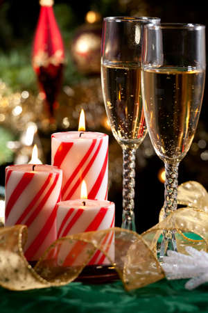 Closeup of peppermint candles, flutes of champaine champagne and Christmas tree with lights out of focus in background.の写真素材