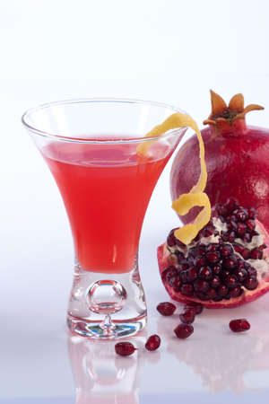Closeup of Pomegranate martini and broken open pomegranate over white. の写真素材