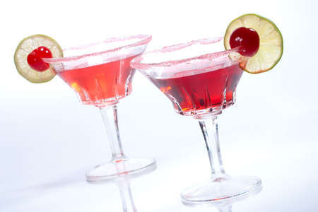 Closeup of two Cosmopolitan cocktails in martini glasses. Vodka, cranberry juice, triple sec liqueur, lime juice, garnished with lime and maraschino cherry. Most popular cocktails series.の写真素材