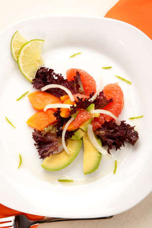 Closeup of papaya, avocado and grapefruit salad with sweet onion and lime wedgesの写真素材