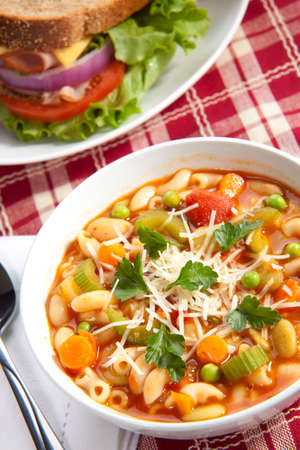 Closeup of bowl of hot fresh Minestrone soup and whole wheat bread turkey breast sandwichの写真素材