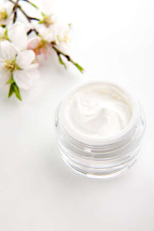 Closeup of jar of moisturizing face cream surrounded by almond flowersの写真素材