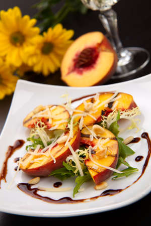 Closeup of grilled peaches salad with Parmesan cheese and roasted pine nuts. Balsamic vinegar sauce.の写真素材