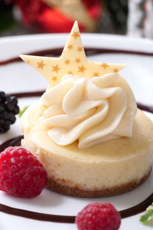 Delicious Vanilla Bean Cheesecake served with fresh blackberries and mint. Christmas ornament out of focus in backgroundの写真素材