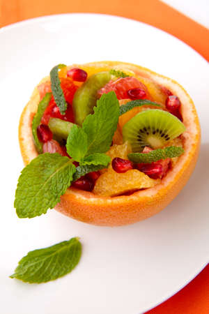Serving of fresh fruit citrus salad in grapefruit peel. Kiwi, grapefruit, orange and pomegranate seeds.の写真素材