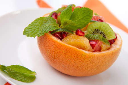 Serving of fresh fruit citrus salad in grapefruit peel. Kiwi, grapefruit, orange and pomegranate seeds.の写真素材