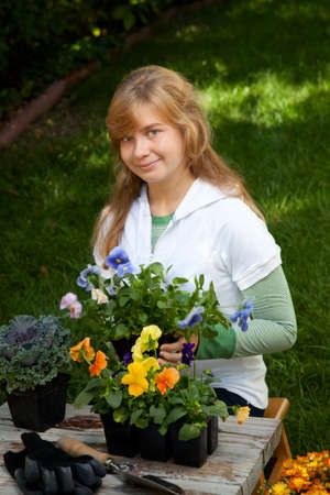 Teenage girl is planting flowers in her backyard gardenの写真素材
