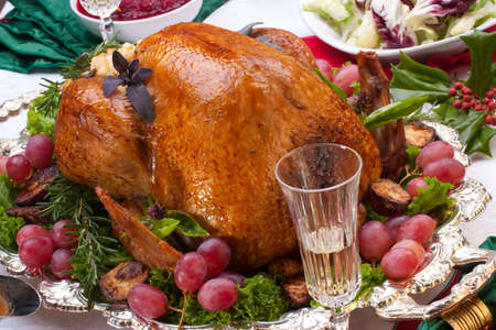 Garnished roasted turkey on Christmas decorated table with candles and flutes of champagneの写真素材