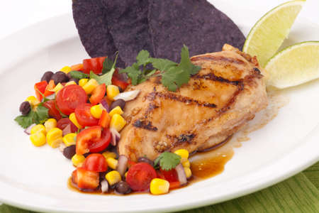 Grilled chicken breast with salsa - black beans, corn, tomatoes, chilli pepper, cilantro, red onion - with  blue corn tortilla chips.の写真素材
