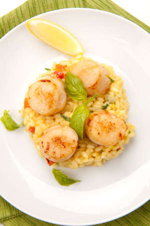 Plate of Scallops Risotto garnished with fresh basil, glass of white wine and bread.の写真素材