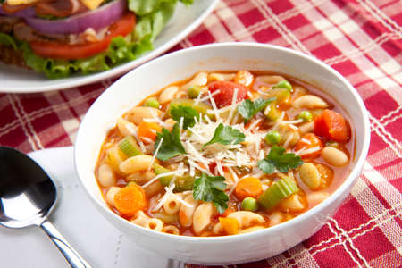 Closeup of bowl of hot fresh Minestrone soup and whole wheat bread turkey breast sandwichの写真素材