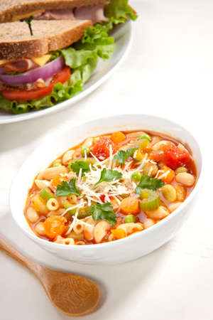 Closeup of bowl of hot fresh Minestrone soup and whole wheat bread turkey breast sandwichの写真素材