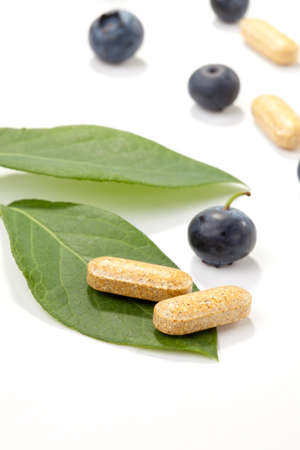 Closeup of bilberry extract pills and fresh berries and leaves best suited for alternative medicine adsの写真素材