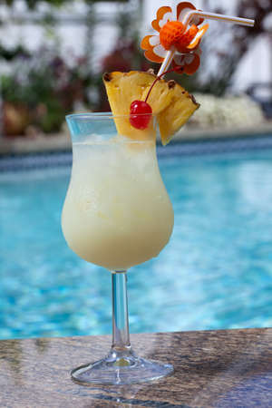 Glass of Pina Colada cocktail on swimming pool sideの写真素材