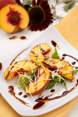 Closeup of grilled peaches salad with Parmesan cheese and roasted pine nuts. Balsamic vinegar sauce.の写真素材