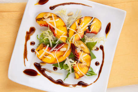 Closeup of grilled peaches salad with Parmesan cheese and roasted pine nuts. Balsamic vinegar sauce.の写真素材