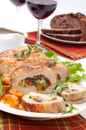 Feta-, spinach-, and bell pepper - stuffed pork tenderloin roulade garnished with sweet potato and green salad.の写真素材