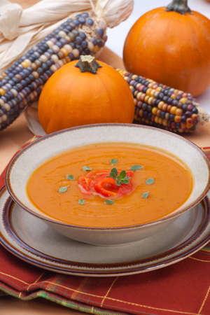 Closeup of a bowl of hot delicious spicy roasted bell pepper pumpkin soup garnished with fresh oreganoの写真素材