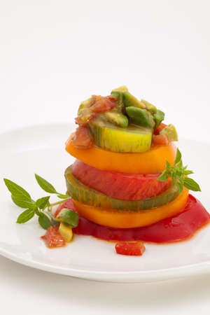 Closeup of Heirloom Tomato Salad with basil avocado salsa over white.の写真素材