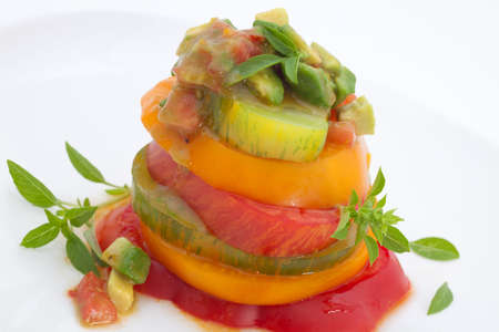 Closeup of Heirloom Tomato Salad with basil avocado salsa over white.の写真素材