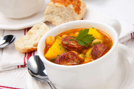 Closeup of bowl of hot fresh golden chorizo and chickpea soup and cheese garlic bunsの写真素材
