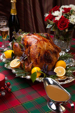 Garnished roast turkey on Christmas-decorated table with candles and flutes of champagneの写真素材