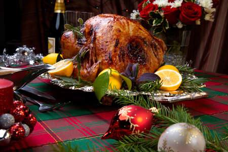 Garnished roast turkey on Christmas-decorated table with candles and flutes of champagneの写真素材