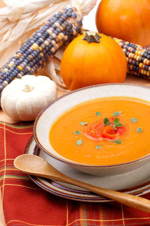 Closeup of a bowl of hot delicious spicy roasted bell pepper pumpkin soup garnished with fresh oreganoの写真素材