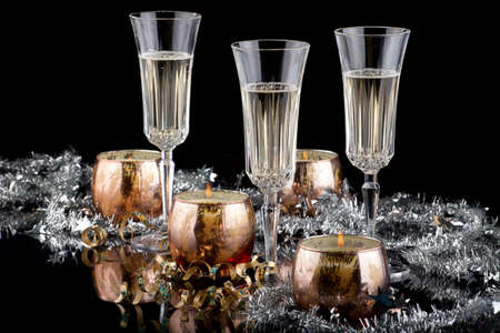 Closeup of flutes of champagne, candles and Christmas decoration on black background.の写真素材