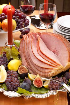 Glazed delicious whole baked honey sliced ham with figs, lemons and champagne grapes.の写真素材