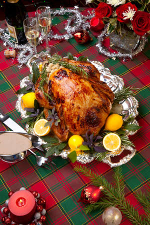 Garnished roast turkey on Christmas-decorated table with candles and flutes of champagneの写真素材