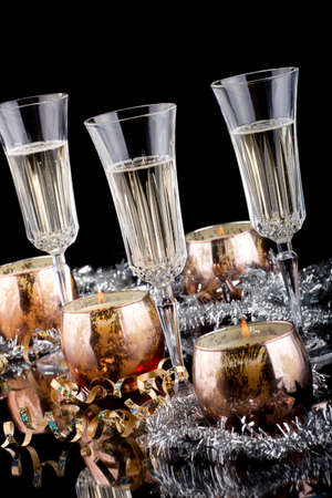 Closeup of flutes of champagne, candles and Christmas decoration on black background.の写真素材