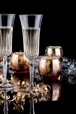 Closeup of flutes of champagne, candles and Christmas decoration on black background.の写真素材