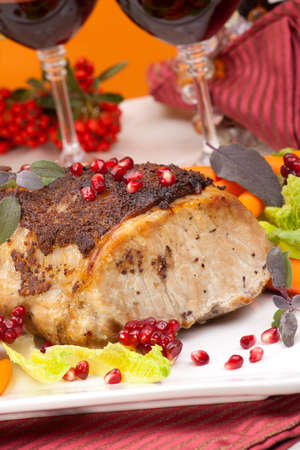 Delicious sliced sage mustard pork tenderloin with vegetables and pomegranate.の写真素材