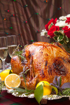 Garnished roast turkey on Christmas-decorated table with candles and flutes of champagneの写真素材